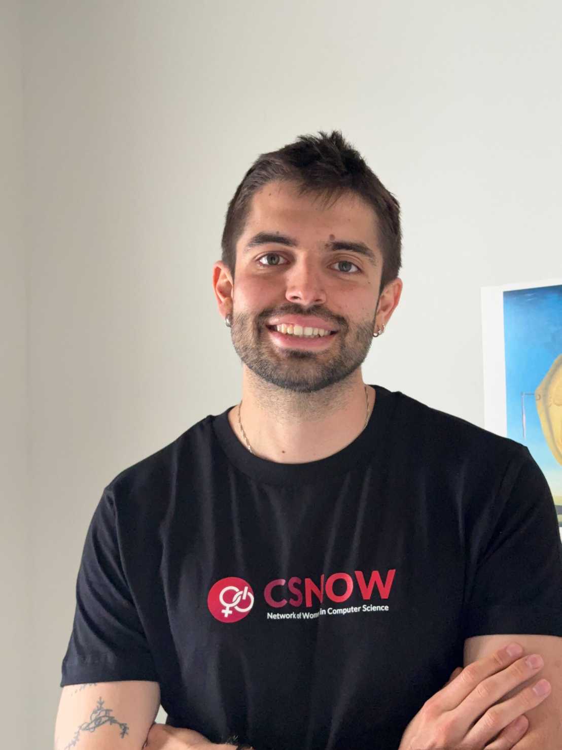 Gonzalo smiling infront of a white background, wearing a CSNOW tshirt